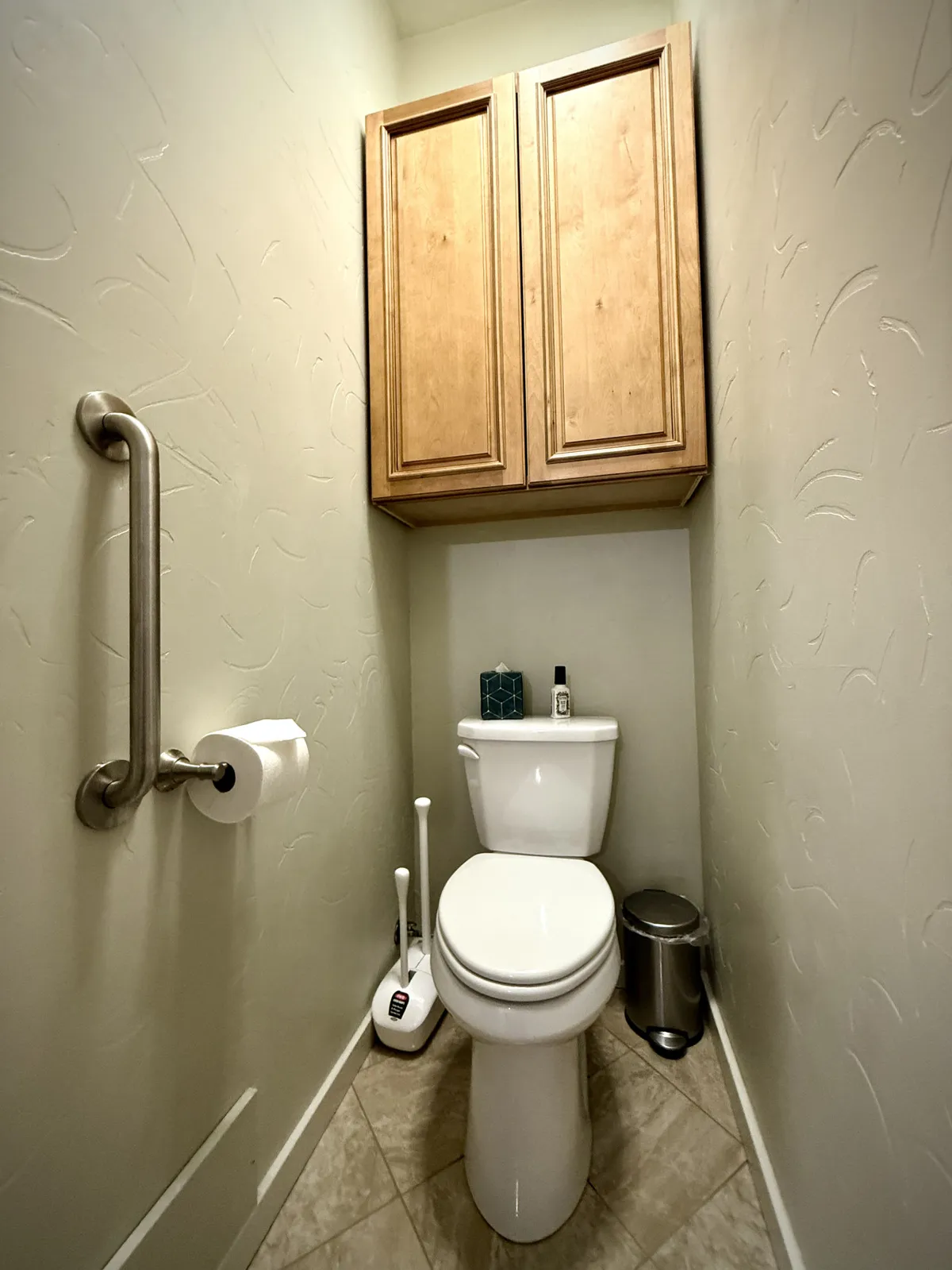 A well-organized toilet room with cabinets, a toilet, and subtle decorative touches. The compact yet clean arrangement offers simple practicality and privacy for guests.