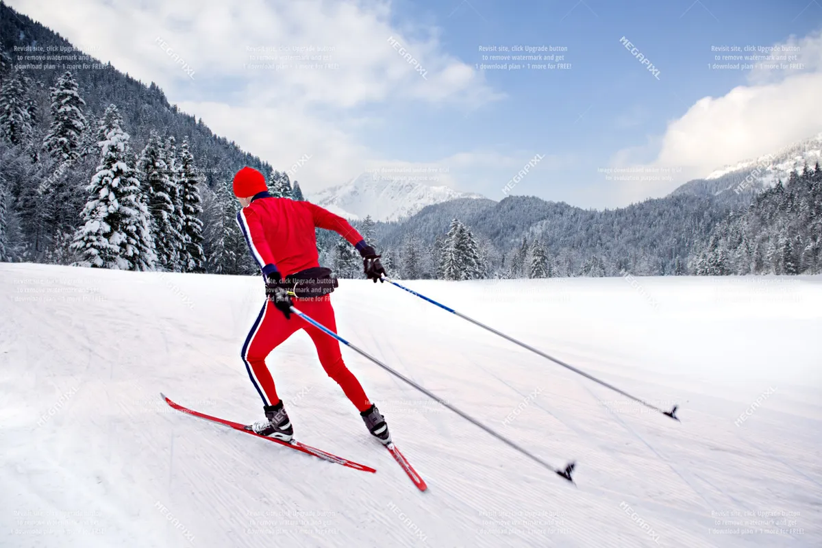 A skier dressed in a striking red outfit glides across a snow-covered landscape, with distant mountains stretching out in the background. The crisp snow and sweeping mountain vistas evoke the thrill and beauty of winter sports in Eastern Oregon.